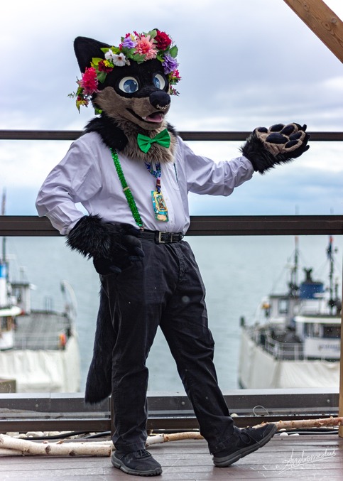 photo of me wearing my fursuit with white shirt, green suspenders, and black pants.